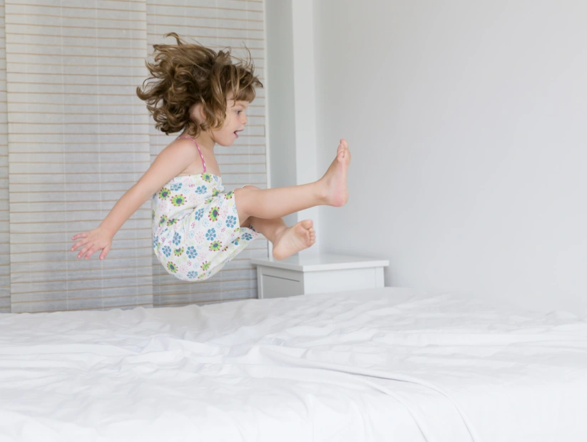 Dziewczynka bezpiecznie bawiąca się na łóżku